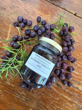 Load image into Gallery viewer, A glass jar of Blueberry Tarragon Jam from Timber House Resort is displayed on a rustic wooden table, surrounded by fresh blueberries and fresh tarragon sprigs.
