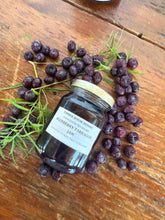 Load image into Gallery viewer, A glass jar of Blueberry Tarragon Jam from Timber House Resort is displayed on a rustic wooden table, surrounded by fresh blueberries and fresh tarragon sprigs.
